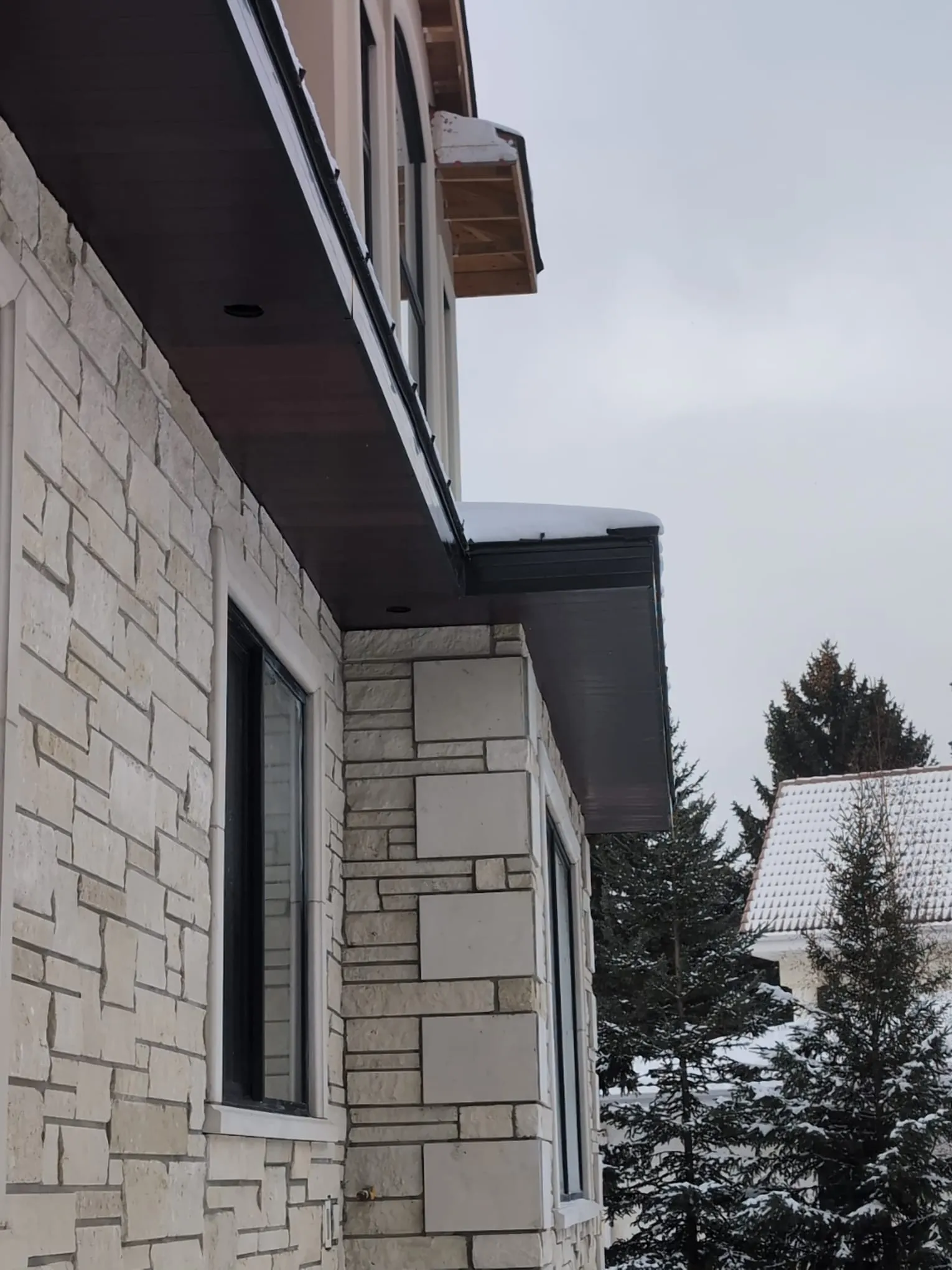 ACR Construction dark soffit and fascia installation on stone exterior wall